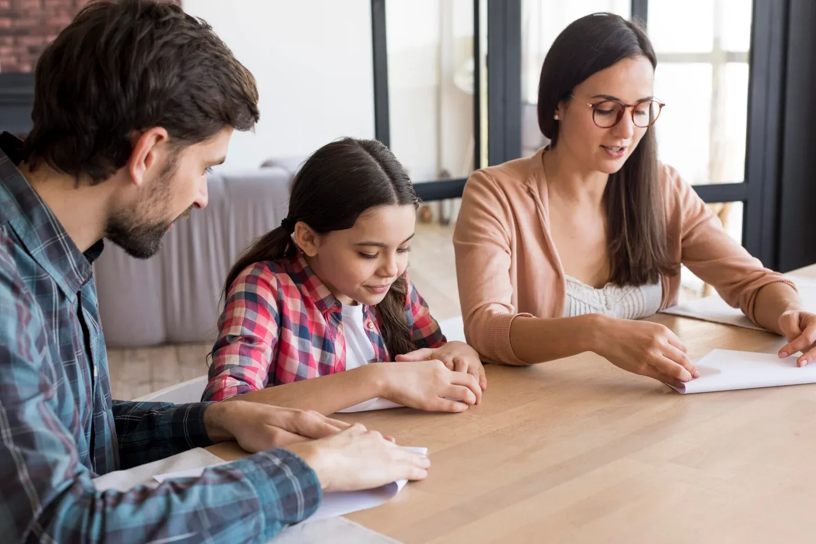 casal e sua filha fazendo o trabalho de casa 